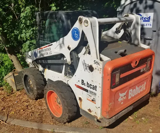 Rear and side view of a Bobcat S570 wheeled skid-steer loader with a bucket.