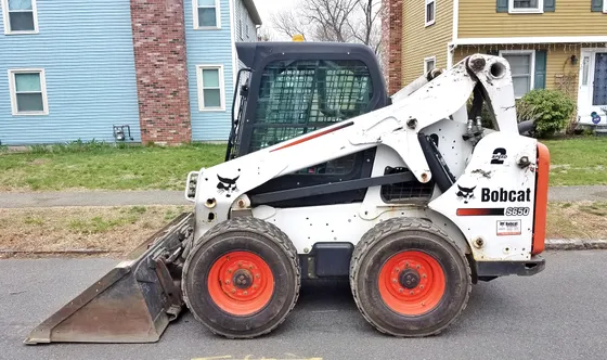 Side view of a Bobcat S650 wheeled skid-steer loader with a bucket.