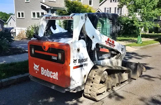 Rear and side view of a Bobcat T590 compact track loader with a bucket; the T590 badge is visible.
