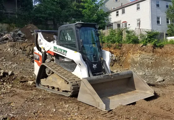 Bobcat T76 compact track loader with a bucket at a residential construction site.