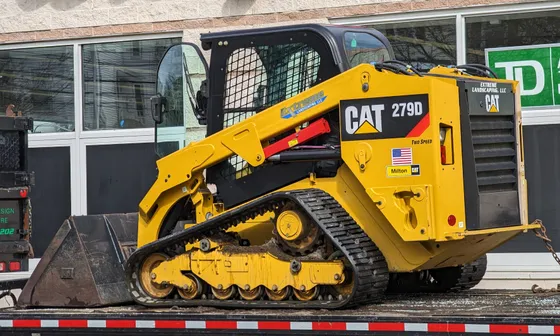 Caterpillar 279D compact track loader with a bucket on a trailer.