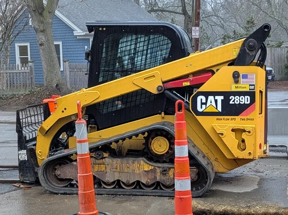 Caterpillar 289D compact track loader marked High Flow XPS, parked beside traffic cones.